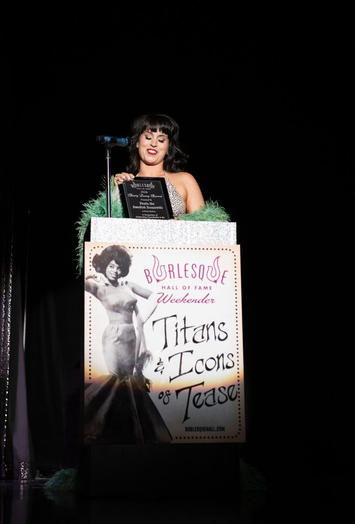 Ginger Valentine accepts Paula the Swedish Housewife's Sassy Lassy Award in Titans and Icons of Tease at the Burlesque Hall of Fame Weekender 2026, by SH Photografia